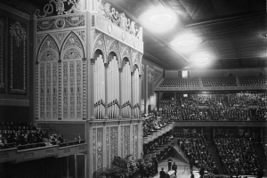 Interior view at the Denver Municipal Auditorium in Denver, Colorado; shows an audience, a pipe organ, and a coffin at the funeral of Mayor Robert Speer.