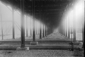 Shows a view of railroad tracks under a portion of the 14th (Fourteenth) Street Viaduct and the supports underneath the bridge. This may be near 14th and Wazee. The viaduct began at 14th and Wazee and ended at 14th and Platte Street. It was later replaced by Speer Boulevard. Construction on the viaduct began in 1897 and was completed in 1899.