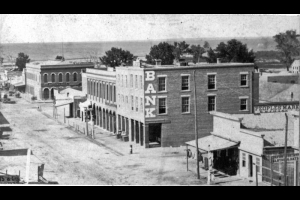 View of 15th (Fifteenth) Street in Denver, Colorado; shows businesses identified as: "Warren Hussey & Co. Bank - nw corner of Holladay & F (15th st.); First Nat. Bank nw cor F & Blake." Sign reads: "People's Market."