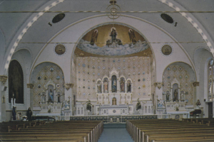 Interior view of Our Lady of Mount Carmel Church (1904 : Frederick Paroth), 3549 Navajo Street in the Highland neighborhood, Denver, Colorado. Shows the ornate Romanesque interior, the altar, pews, ceiling, wall murals and tile work, and painted statues.