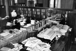 View of the Western History department in the Denver Public Library at Colfax Avenue and Bannock Street in the Civic Center neighborhood of Denver, Colorado. A man and woman stand and sit near a desk. Books and newspapers are in the room.