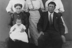 Studio group portrait taken at the time of the baptism of Mercedes Gómez in Vigil (Las Animas County), Colorado. Members of the Hispanic American Gómez family are identified: top left to right: Carolina Gómez, Lucía Gómez, Domecinda Gómez. Front, left-right: Juanita M. Girardot Gómez, Mercedes Gómez (baby). and Leandro Gómez.