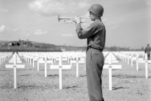 A bugler plays taps beside the rows of white crosses that mark the graves of servicemen who died in the Italian campaign during a memorial service held for the men of the Tenth Mountain Division on April 6, 1945, at the American Cemetery in Castelfiorentino (Florence Province), Italy.
