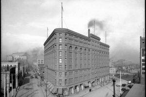 Exterior view of Brown Palace Hotel, Denver, Colorado; shows overview of hotel, streets, street car tracks, and wagons at the intersection of Broadway and 17th (Seventeenth) Street; backside of Equitable Building distant left and Denver High School, distant right.