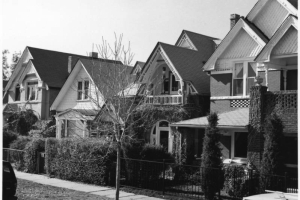 View of homes in the Baker Neighborhood of Denver, Colorado; features include shingle imbrication, covered porches, bargeboard, arched windows, corbeled brick, and an inset balcony.