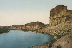 View of eroded striated bluffs and cliffs, the pillar Tollgate Rock and The Palisades on Green River in Sweetwater County, Wyoming.