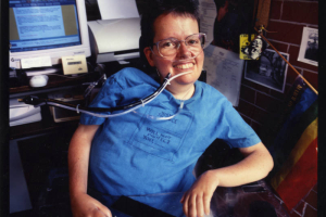 Portrait of Laura Hershey seated by her desk. Photographer unknown.