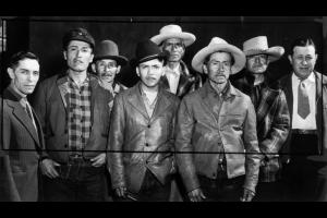 Studio portrait of Native American (Navajo) men probably in Colorado. They wear hats and jackets. One man wears a tie.